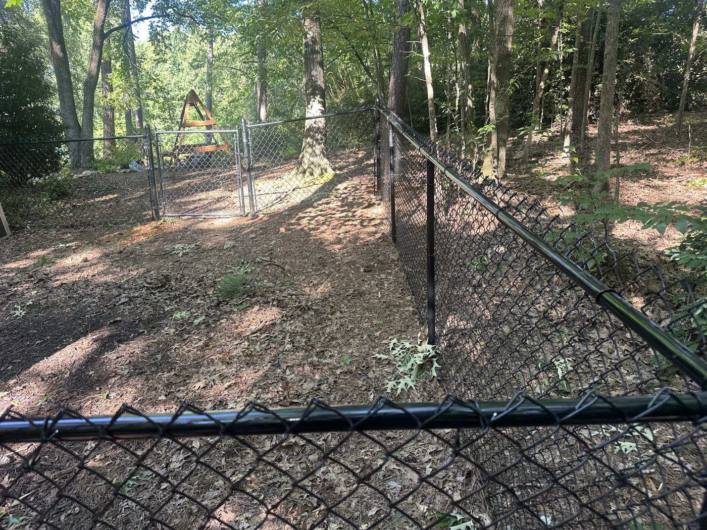 Black chain-link fence stepped down a sloped backyard — Precision Palmetto, Columbia SC