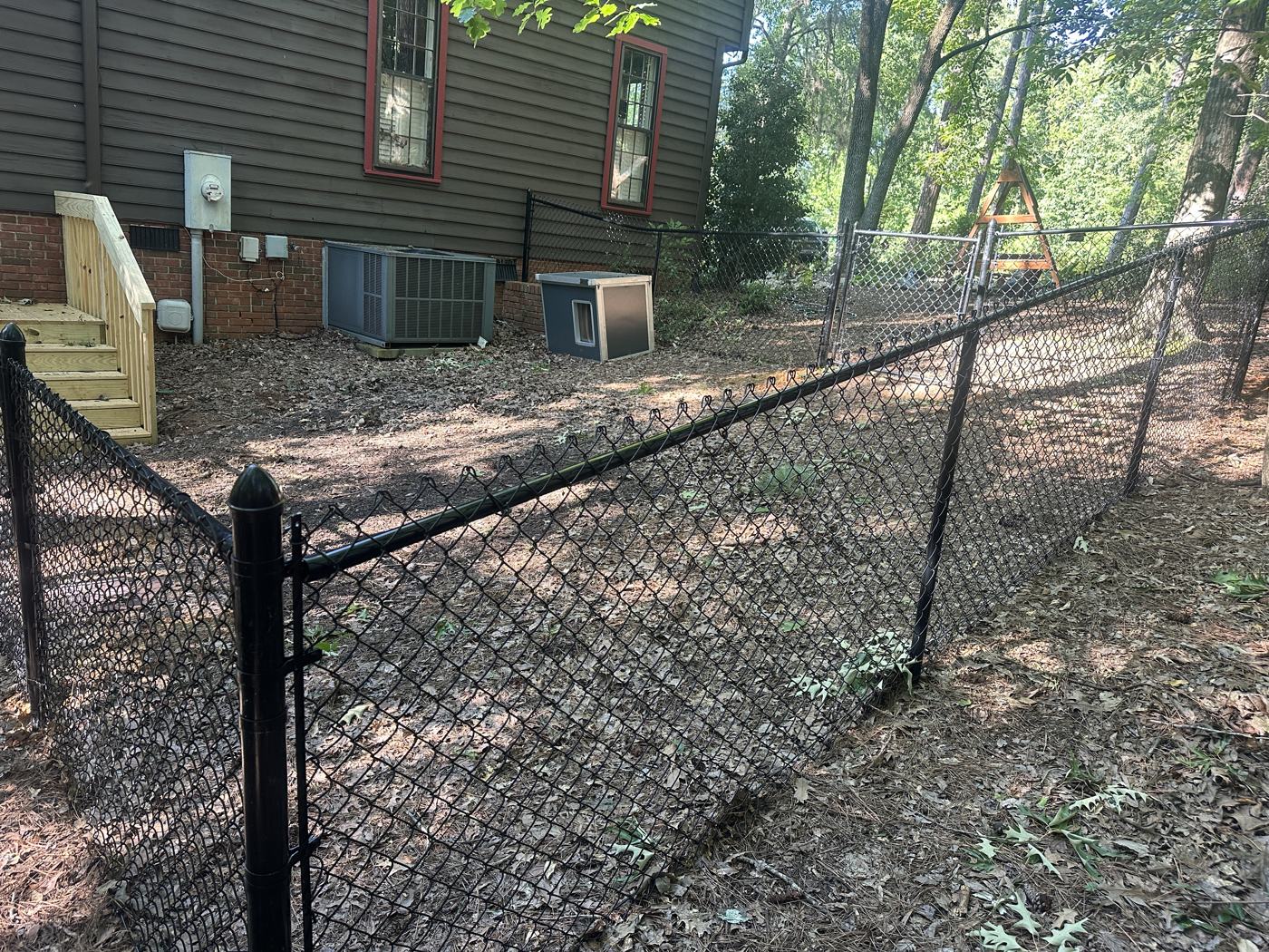 Gate posts and hardware — black chain-link on a slope — Precision Palmetto, Columbia SC